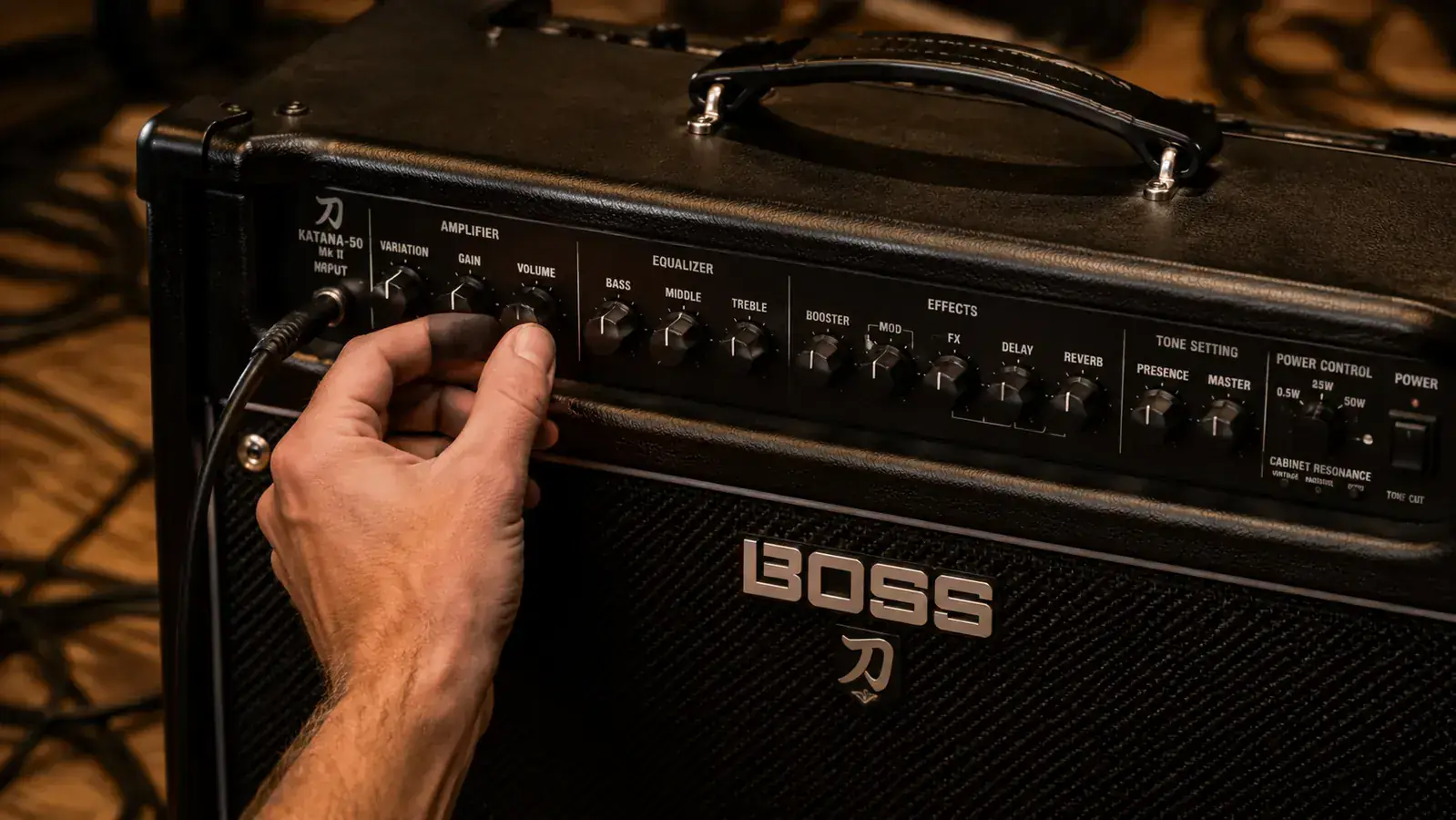 Close-up of a guitarist's hand reaching for the gain knob on the Boss Katana MkII-50